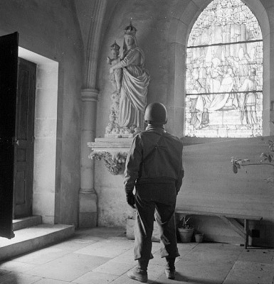 A soldier looks at a statue of Mary and Jesus, probably in a church in Europe during World War II. Courtesy Library of Congress.
